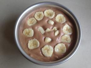 将蛋糕糊从20CM左右的高度倒入到6寸的阳极活底蛋糕模里，在桌面上震出气泡。香蕉切小块，放在蛋糕糊上面