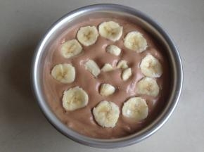 将蛋糕糊从20CM左右的高度倒入到6寸的阳极活底蛋糕模里，在桌面上震出气泡。香蕉切小块，放在蛋糕糊上面