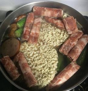 将烧开的汤底倒入码放好食材的汤锅中，煮沸，大约七八分钟左右待食材煮熟，下面饼和肉卷