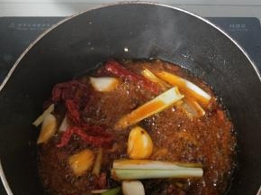 油锅温度升起将黄豆酱，豆瓣酱，蒜瓣，干辣皮小火爆香