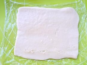 将保鲜膜上的原色面团，用擀面杖擀成0.2厘米厚的长方形