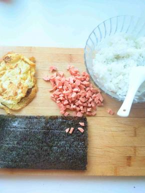 鸡蛋饼放凉，火腿肠切丁，准备好海苔，米饭备用
