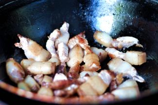 3、锅中放入少量色拉油，烧至6成热时，倒入焯过水的五花肉小火翻炒，炒至五花肉变成金黄色，这时锅中的油脂变多，放入料酒和一点醋，去掉肉上的腥味，然后将肉盛出沥干净油备用。