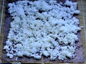 4、寿司帘上放上紫菜，将米饭辅匀在紫菜上。