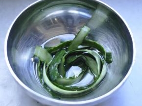 1、黄瓜洗净，用刮皮刀把黄瓜皮顺长条刮下来，放入热盐水中浸泡备用。。