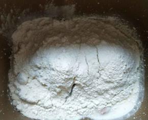 放入高筋面粉、全麦粉，最后挖个坑放入酵母。启动揉面程序20分钟。