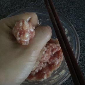 然后转至小火。把搅拌均匀后的肉酱用手抓出小丸子状，用筷子夹托放入油里慢火炸