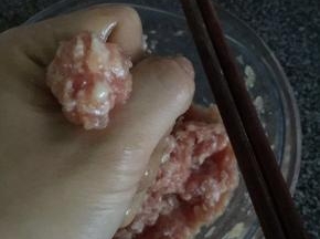 然后转至小火。把搅拌均匀后的肉酱用手抓出小丸子状，用筷子夹托放入油里慢火炸