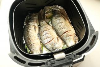 扎锅内铺锡纸，葱段和姜片铺在锡纸上，放上鲫鱼，表面刷少许油。