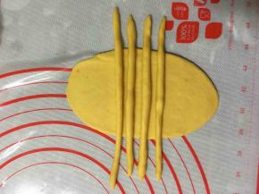 将搓好的四个长条放在牛舌状的面片上。