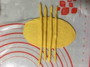 将搓好的四个长条放在牛舌状的面片上。