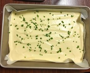 搅拌混合好的蛋糕糊倒入烤盘，震出气泡，然后撒上葱花