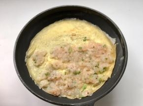 待蛋皮即将凝固时将虾泥均匀放在蛋皮上（留一小半方便卷收口，不需要整张蛋皮都要放虾仁泥）