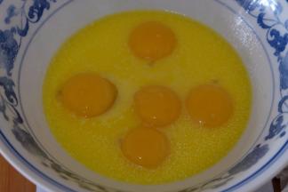 将五个鸡蛋的蛋黄也敲在大碗里；（蛋清放在一个无油无水的打蛋盆里待用）