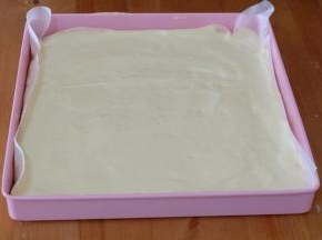 正方烤盘里铺上烘焙油纸，然后把蛋糕糊倒在油纸上，用刮刀刮平；