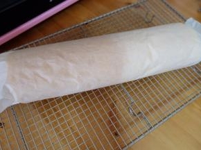 等蛋糕胚子温热以后，另取一张干净的烘焙油纸，将蛋糕卷起来，用油纸把蛋糕包好，使蛋糕卷形状固定；
