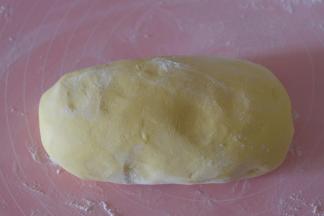 将盆里的面团转移到揉面垫上，撒一些干面粉，用手揉至光滑；