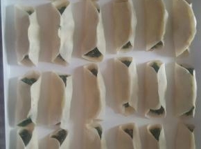 拿起面片放在手上，抹上馅料，中间捏紧两头不要捏，摆到烤盘上