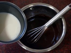 将刚煮沸腾的牛奶倒入可可粉蛋黄面糊中，边倒边搅拌，然后将混合物过筛，重新倒入奶锅中。