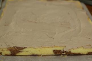 蛋糕片一端斜切一刀，抹上奶油至另一端1cm左右停止。奶油中间高，两端低。「两端不需要抹太满，以免卷时爆出来」