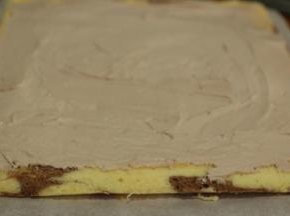 蛋糕片一端斜切一刀，抹上奶油至另一端1cm左右停止。奶油中间高，两端低。「两端不需要抹太满，以免卷时爆出来」