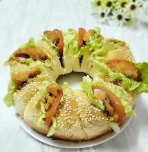 每个小面包中间割一刀，抹上沙拉酱，夹上生菜、西红柿和炸好的鸡肉即可