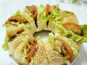 每个小面包中间割一刀，抹上沙拉酱，夹上生菜、西红柿和炸好的鸡肉即可