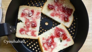 土司对半切开放在炸蓝中，土司比较大，小土司可以不用切，抹上一层樱桃酱或者番茄沙司，撒一点芝士粉