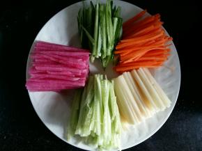 蔬菜都切成长度相等，宽度差不多的丝。黄瓜切的时候可以先把皮削掉，切成绿色的丝。黄瓜的心也切成丝做浅绿色。黄瓜可以做出来2个颜色。