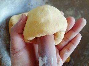 用擀面杖的头粘上面粉从面团中间向里面推。一边推一边转面团，手稍微整理一下表面。