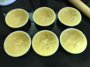 按压成薄面片放入挞模，捏紧使它贴合挞模的边缘。