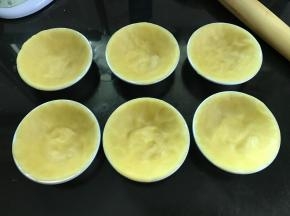 按压成薄面片放入挞模，捏紧使它贴合挞模的边缘。