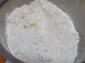 现在来做派皮，准备辅料表里的食材，先把黄油切成小块，不用软化，直接切小块就可以了，放进一个小盆里，再倒进低筋面粉和白糖；