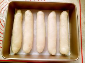 把卷好的面团收口朝下放在阳晨11寸深长方烤盘里盖保鲜膜进行二发。温度不要超过38度（50分钟左右）。