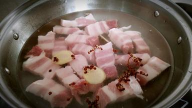 锅中注水，放入五花肉，花椒粒，姜片煮开戳水。
