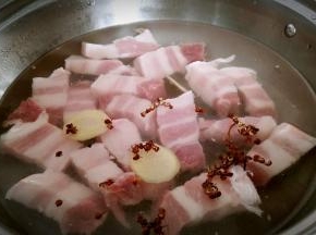 锅中注水，放入五花肉，花椒粒，姜片煮开戳水。