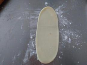 取一个面团，从中间往两头擀成牛舌状。