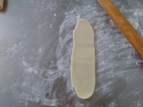取一个醒发好的卷稍微按扁，再次擀成牛舌状。