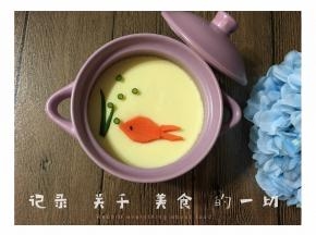 用胡萝卜切成金鱼形状，葱花切成水泡和水草的形状，黑芝麻点缀鱼眼睛装饰在蛋羹上。
蒸好的蛋羹上面也可以撒上葱花，生抽、香油，可根据个人口味添加。也可以蒸的时候加些肉沫，味道也不错哦！
一碗滑嫩美味，沁人肺腑的蛋羹就完成啦！