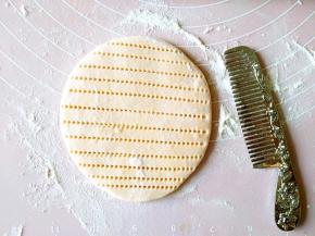 取一小块儿面团擀圆，用洁净的梳子压出纹路。