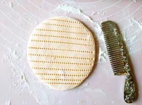 取一小块儿面团擀圆，用洁净的梳子压出纹路。