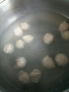 锅里烧开水，开始挤丸子。抓一小把肉泥，从虎口出挤出肉泥，右手用一个勺子把挤出来的丸子盛上，放入开水中。