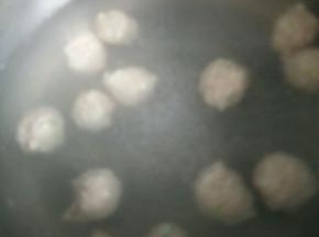 锅里烧开水，开始挤丸子。抓一小把肉泥，从虎口出挤出肉泥，右手用一个勺子把挤出来的丸子盛上，放入开水中。