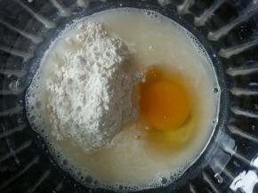 在小米浆中加入少许面粉，一颗鸡蛋。搅拌均匀。面粉也可以最后加，到一定要少量多次加入。