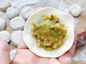 将面片拖在手掌，加调好的馅儿。