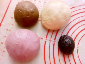 取出面团排气后，平均分成需要的份数，分别加上可可粉、紫薯粉、竹炭粉揉好。（这里的颜色根据自已需要调整），之后滚圆盖保鲜膜松弛20分钟。