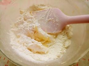 将低筋面粉、奶粉、盐和泡打粉混合后筛入打好的黄油中，切拌均匀。