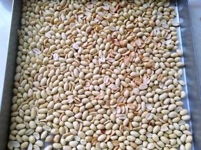 做牛轧糖要一气呵成，先将所有材料准备好，再准备不粘烤盘，裁好的油纸，一碗冷水，花生入烤箱170度烤8至10分钟，之后去皮备用