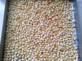 做牛轧糖要一气呵成，先将所有材料准备好，再准备不粘烤盘，裁好的油纸，一碗冷水，花生入烤箱170度烤8至10分钟，之后去皮备用