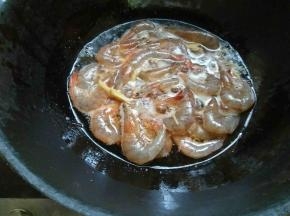 腌好的虾沥干水，起锅热油，放入花椒粒，姜丝爆香。放入大虾，大火炸制一分钟使外壳水分变干。